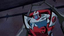 a red and white robot with a shield and a transformer logo on it