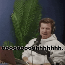 a man wearing headphones is sitting in front of a microphone with a laptop .