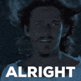 a man with long hair and a beard is standing in front of a sign that says " alright "