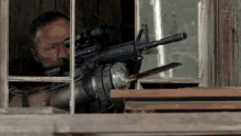 a man is holding a rifle in a window
