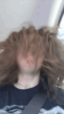 a person with their hair blowing in the wind wearing a black shirt