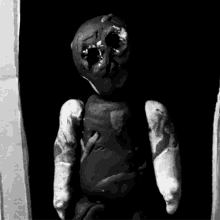a black and white photo of a doll with a hole in the head