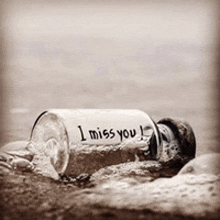 a glass bottle that says i miss you is laying on the ground
