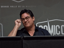 a man wipes his eyes in front of a sign that says comic