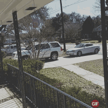 a white car is parked on the side of the road in front of a fence