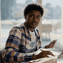 a man is sitting at a table with a netflix logo on the bottom right