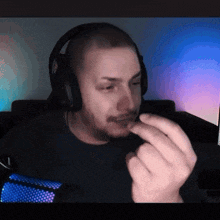 a man wearing headphones is eating something in front of a computer monitor