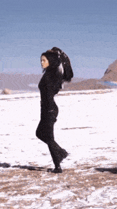 a woman in a black suit is standing in the snow holding an eagle 's feathers .
