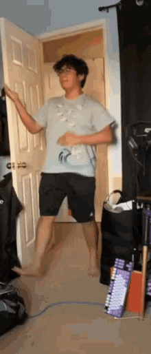 a man in a blue shirt and black shorts is standing in front of a door
