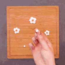 a person is holding a white flower in their hand on a wooden cutting board