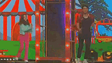 a man and a woman are dancing on a stage in front of a carnival tent