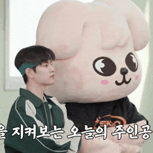 a man standing next to a stuffed animal with korean writing on the bottom