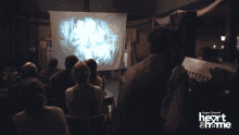 a group of people sitting in front of a projector screen that says super channel heart & home