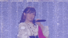 a woman singing into a microphone in front of a blue background