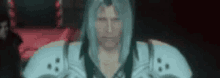 a man with long blue hair is standing in a dark room with a red background .
