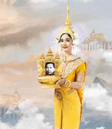 a woman in a yellow dress is holding a statue with a picture of a man in it