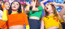 a group of women are standing next to each other on a stage wearing crop tops .