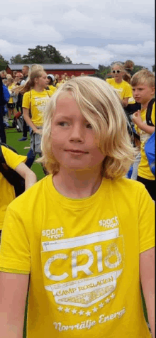 a young boy with blonde hair is wearing a yellow shirt that says cri8