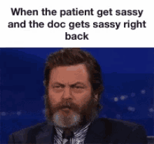 a man with a beard is wearing a suit and tie and is talking into a microphone .