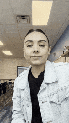 a woman in a denim jacket is standing in front of a classroom