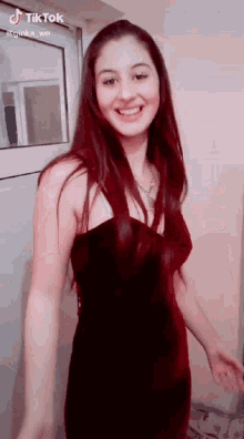 a woman in a red dress is smiling and standing in front of a glass door .