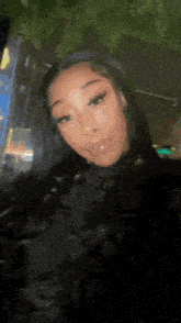 a woman with long black hair is taking a selfie in front of a building at night .