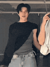 a man in a black shirt is standing next to another man in grey jeans