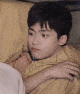 a young boy is laying on a bed with a pillow on his head