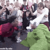 a group of people are gathered around a man in a green blanket