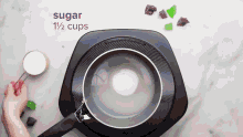 a person is measuring sugar in a measuring cup in a pot .