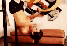 a shirtless man is doing a handstand in front of a painting on a wall .
