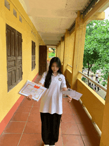 a girl in a white shirt is holding a certificate with a red envelope
