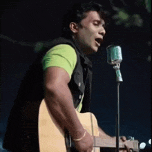 a man singing into a microphone while holding a guitar .