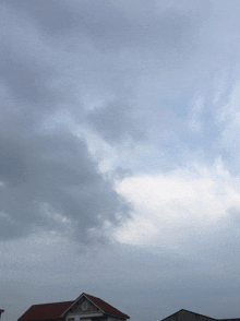 a house with a red roof and a cloudy sky