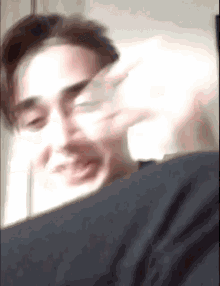a blurry picture of a man making a funny face with his hand
