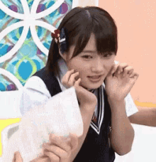 a girl with a flower in her hair is making a funny face while holding a piece of paper .