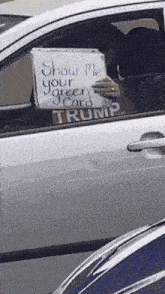 a white car with a sign in the window that says show me your green card