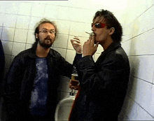 a man smoking a cigarette next to another man holding a beer