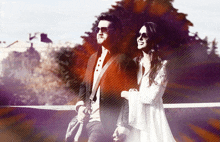 a man and a woman standing next to each other with trees in the background