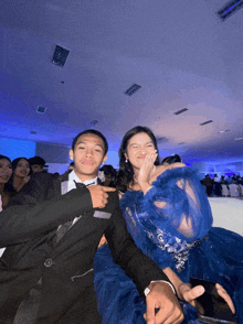 a man in a tuxedo and a woman in a blue dress pose for a picture