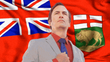a man in a suit and tie stands in front of a british flag and a canadian flag