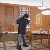 a man is dancing in a dining room in front of a table .