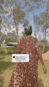 a woman in a leopard print dress is walking in the grass