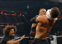 a wrestling match is going on in front of a crowd with a raw banner behind them