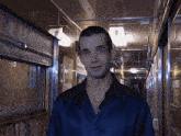 a man wearing a blue shirt is standing in a hallway