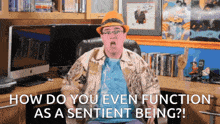 a man sitting in front of a desk with the words " how do you even function as a sentient being " above him