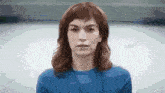 a woman wearing a blue shirt and a lanyard is looking at the camera .