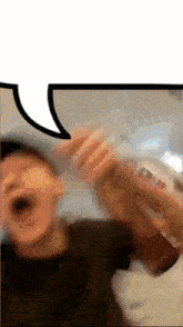 a blurry picture of a man holding a bottle with a speech bubble above him