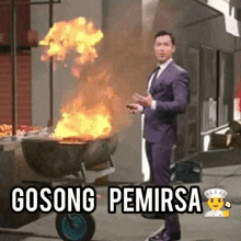 a man in a suit and tie is standing next to a wheelbarrow full of flames .