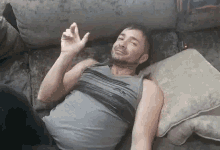 a man is laying on a couch with a pillow and a cigarette in his hand .